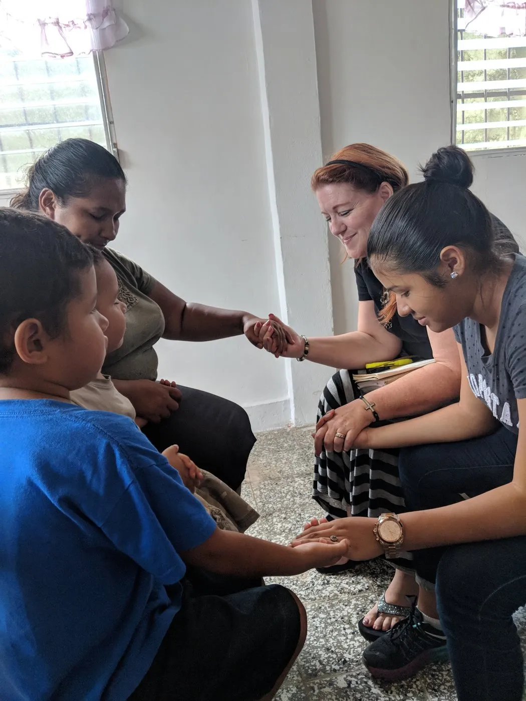 Loring praying hand in hand with a Honduran woman and child.
