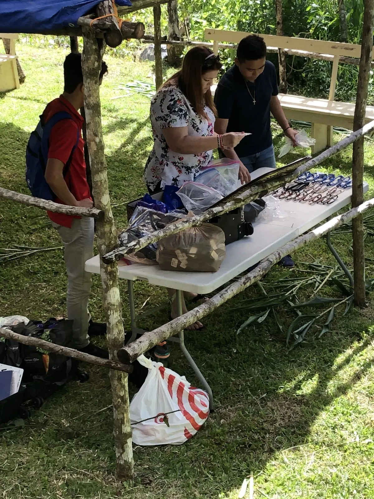A team distributing supplies at an outdoor table under a canopy.